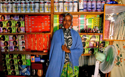 Diese Frau, die 2008 aus Somalia nach Kenia geflüchtet ist, betreibt im Lagerkomplex Dadaab einen Schönheitssalon. Im Jahr des Fotos, 2012, leben in Dadaab nach Angaben des UNHCR weit über 400.000 Menschen – manche von ihnen schon seit Anfang der 1990er-Jahre. In solchen großen Agglomerationen sind im Laufe der Zeit eigene Ökonomien und soziale Infrastrukturen entstanden. Inzwischen ist die Zahl der Bewohner/innen von Dadaab gesunken, aber viele Menschen können oder wollen nicht nach Somalia zurückkehren.(Wikimedia Commons, Oxfam East Africa, Inside the beauty salon (7550608684), CC BY 2.0)