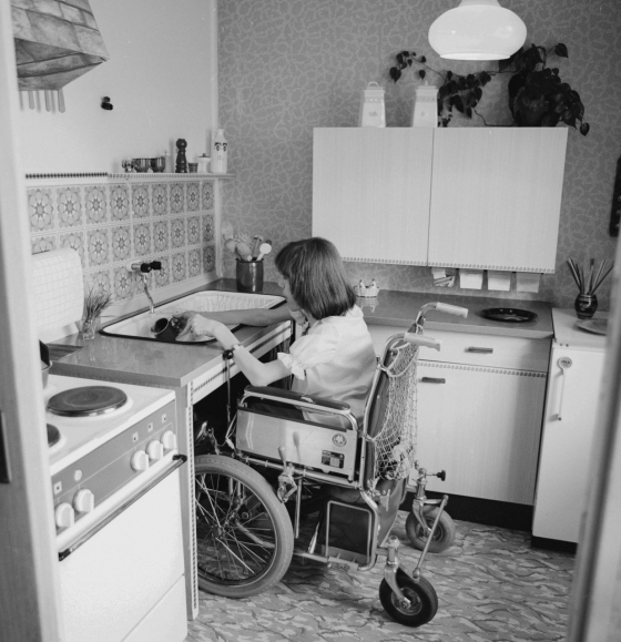 Unterfahrbare Spülbecken und niedriger gehängte Küchenschränke erleichterten Menschen im Rollstuhl die tägliche Hausarbeit, wie hier in einer Wohnung in Ost-Berlin (1979). (picture-alliance/ddrbildarchiv/Manfred Uhlenhut)