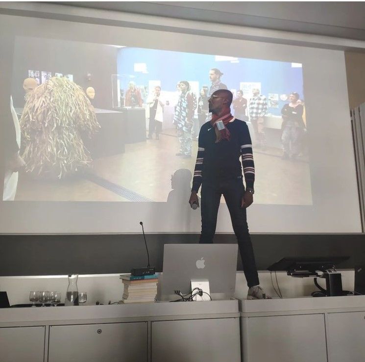 Désiré Amani, ivorischer Wissenschaftler und Künstler, bei seiner Performance während der Konferenz zum Archiv von Hans Himmelheber: Amani reagiert auf die Filmaufnahmen seiner früheren Performance in der Ausstellung »Look Closer«. (Universität Zürich, April 2023, Foto: Gesine Krüger)