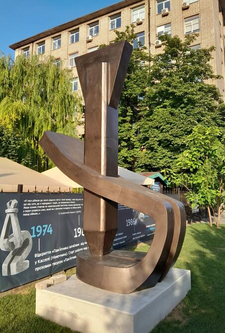 Kopie von Vadim Sidurs Tod durch Bomben in Dnipro, aufgestellt zum 100. Geburtstag des Künstlers. Auf dem Plakat im Hintergrund ist sein Werk Der Gefesselte zu sehen.